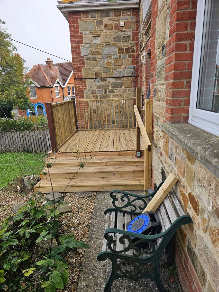 New raised timber decking with steps and balustrade beside a stone house