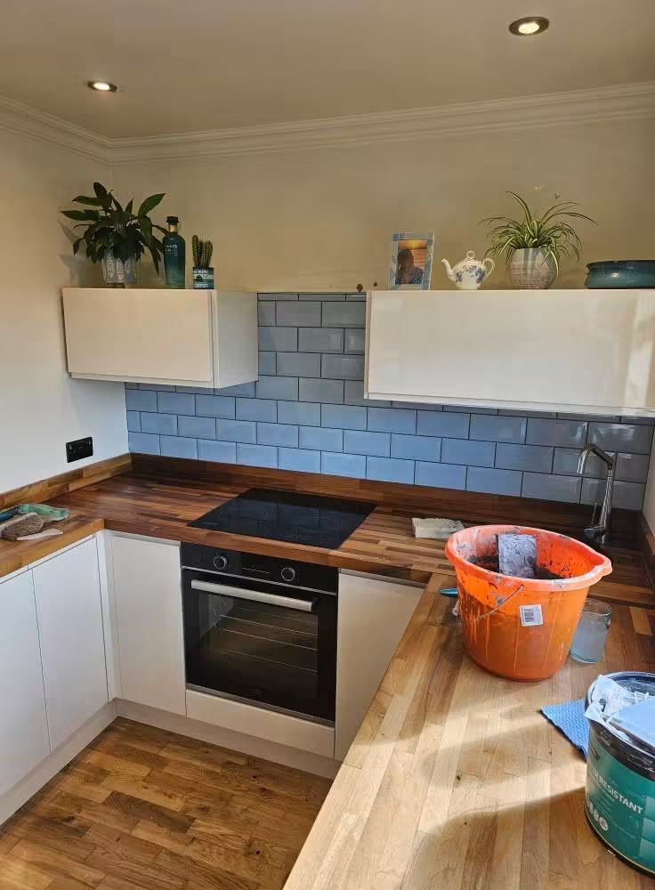 Kitchen with blue tiled splashback and wooden worktops